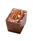A chocolate candy with caramel and nuts, topped with flaky salt.