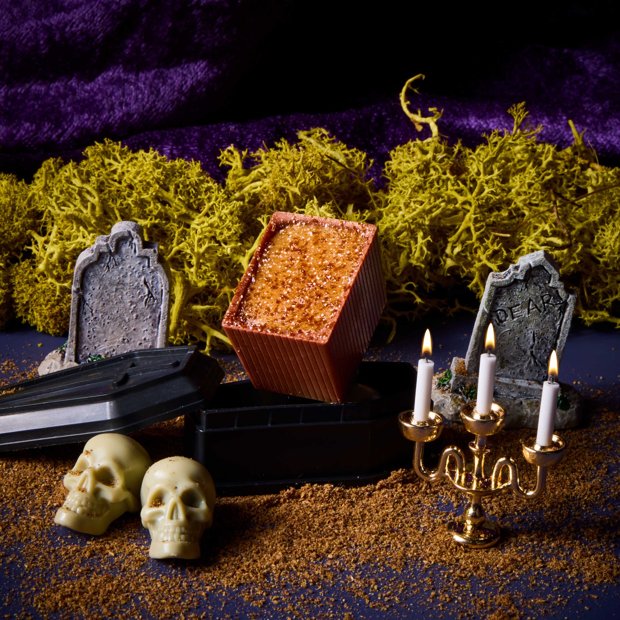 Spiced Sweet Tato Bon on a black coffin beside two gravestones