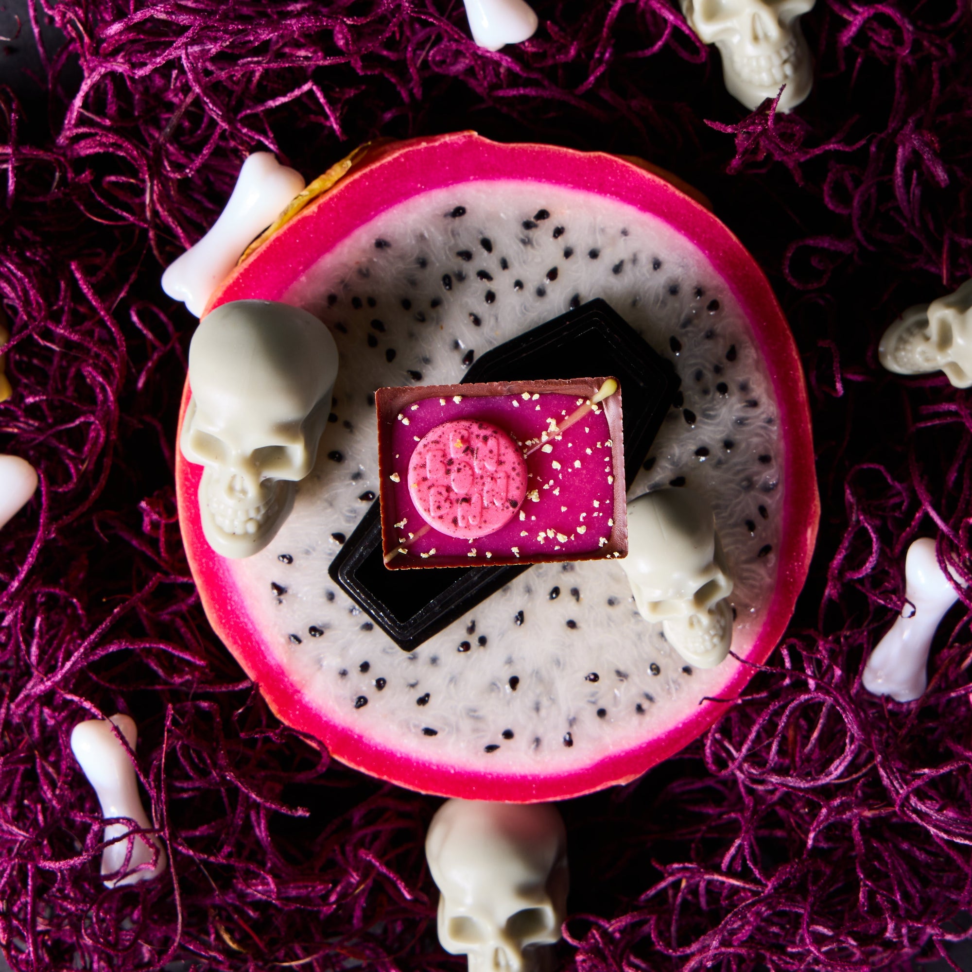 Pansy Dragon Bon atop half a dragonfruit with skulls and bones in the background