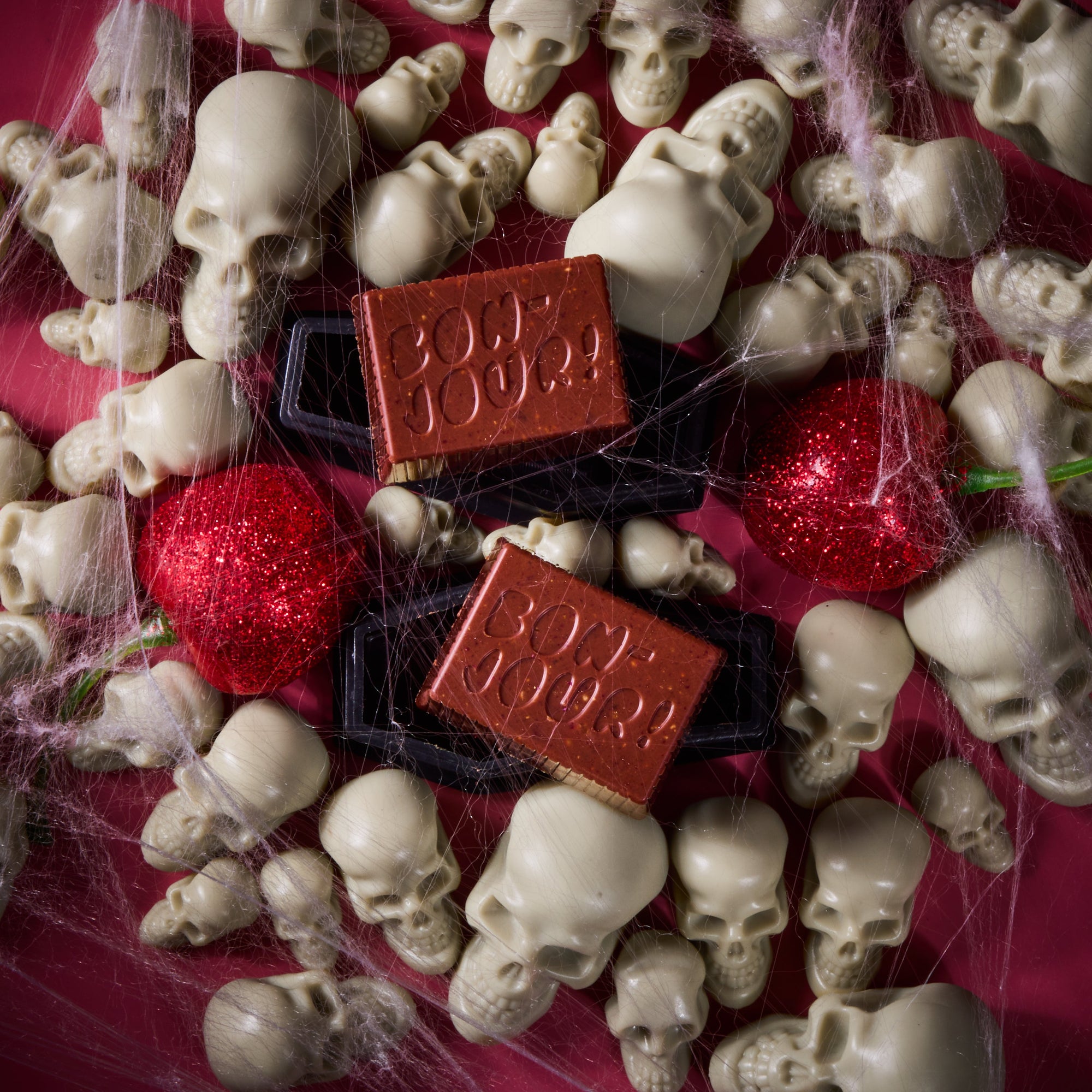 Milk Chocolate Bon on a bed of skulls with cherries and spider webs