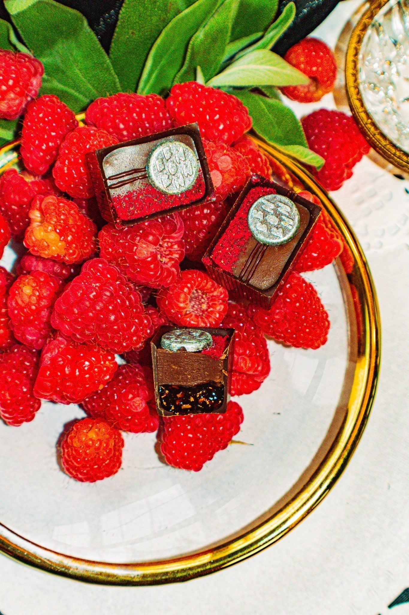 Three Bons on top of a heap of sage and raspberries on a china plate.