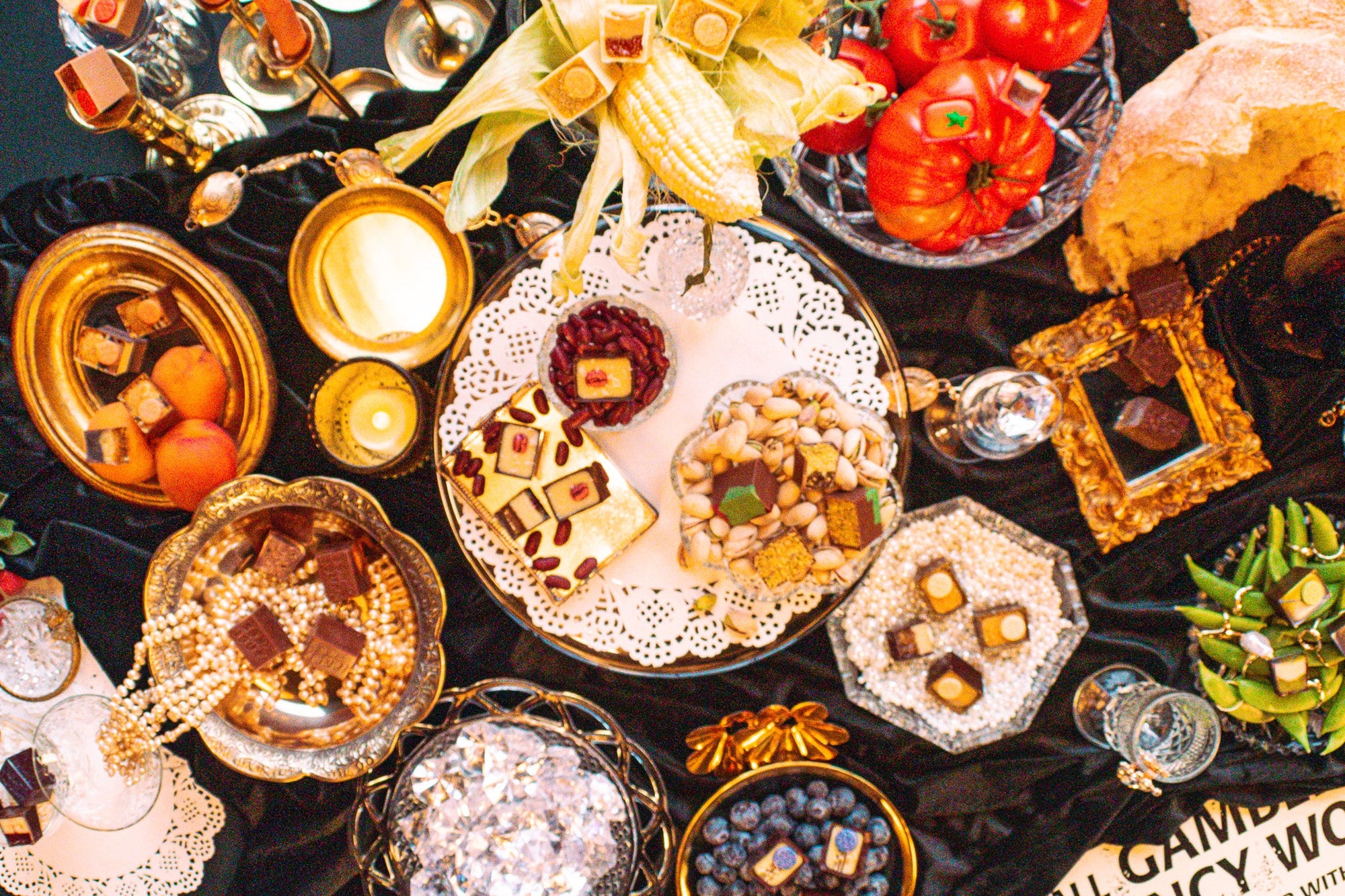 A spread of fancy plates and jewelry on a black tablecloth