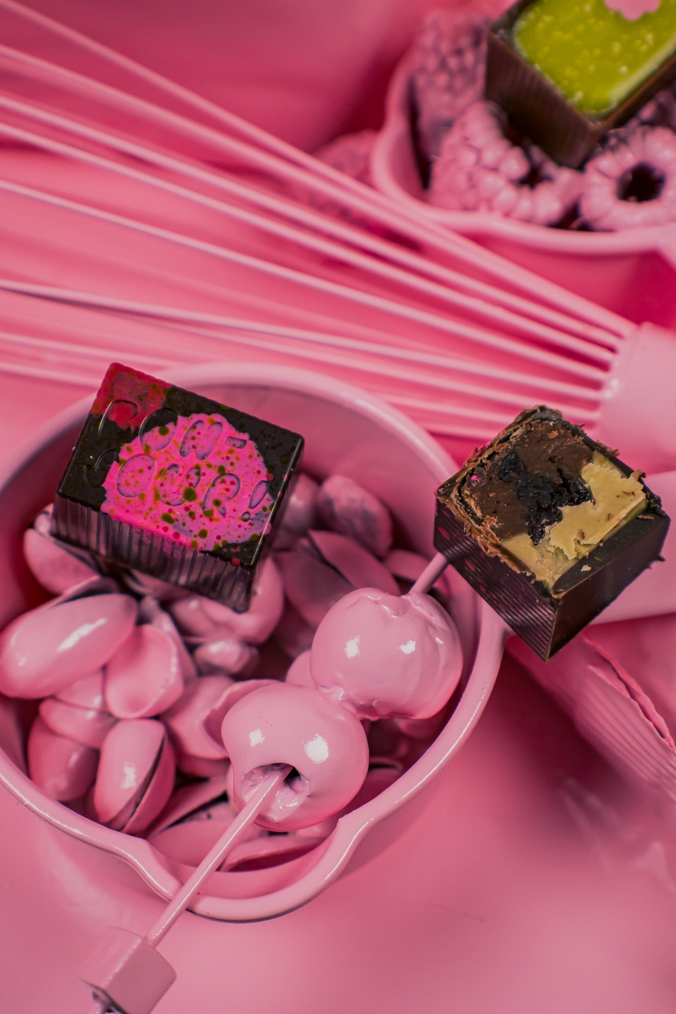 Pink bowl of spray painted pink pistachios and cherries with a Bon and half a Bon on top.