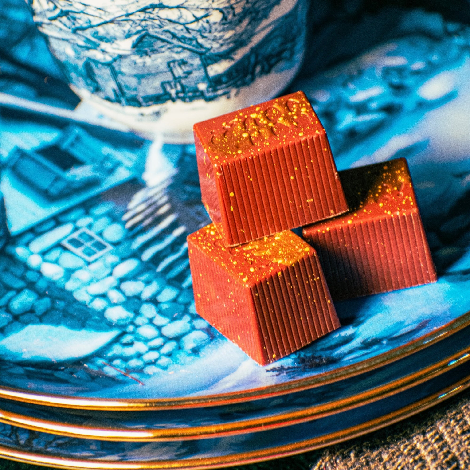 Three Gran's Toffee Bons sitting on a blue plate with a gold edge