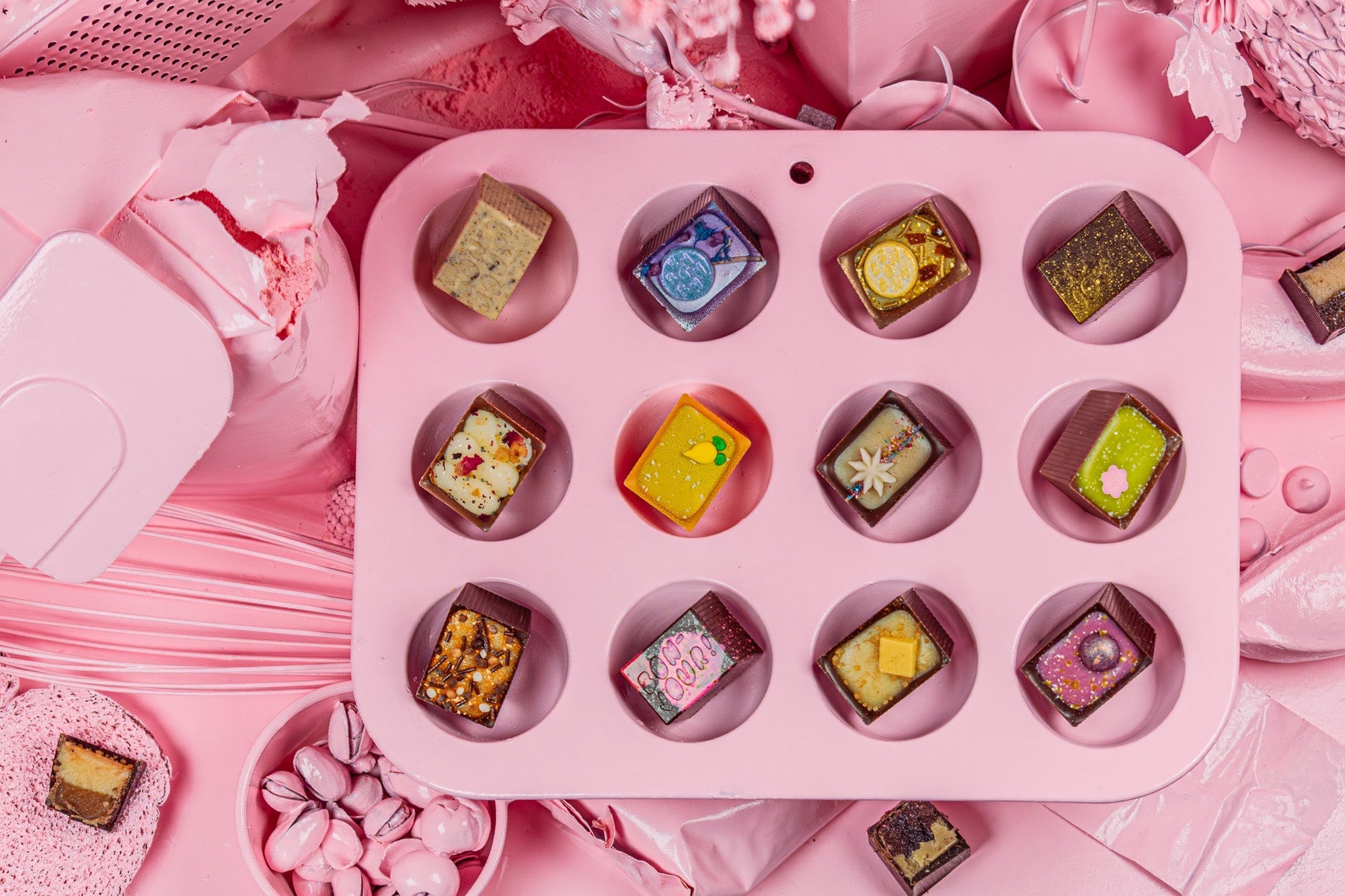 Pink 3x4 muffin tin with a Bon in each divot. Pink pray painted objects in the background 