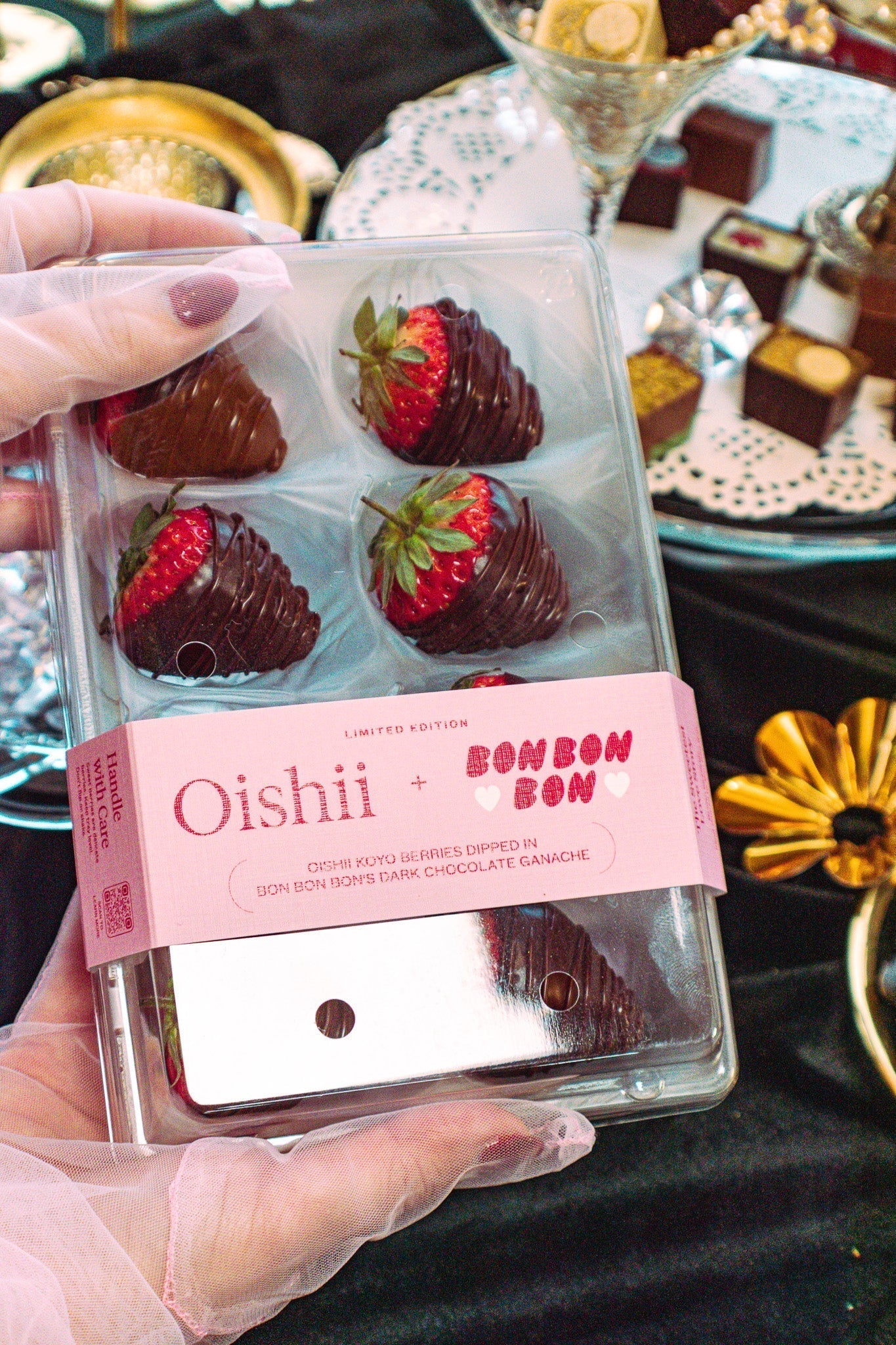 Plastic box of 6 chocolate covered strawberries with Bons in the background.