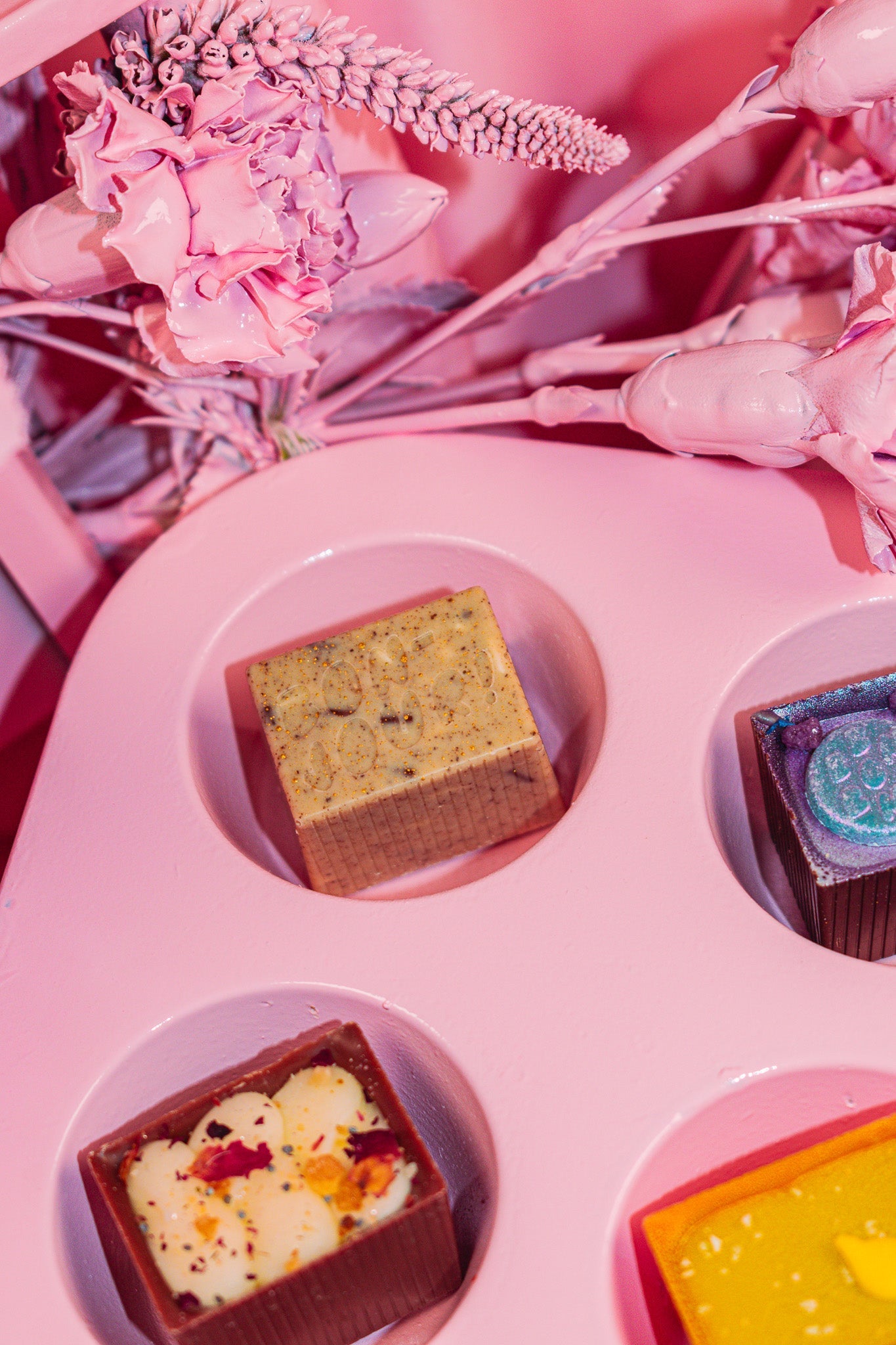 One Bon in the divot of a muffin tin that is pink!