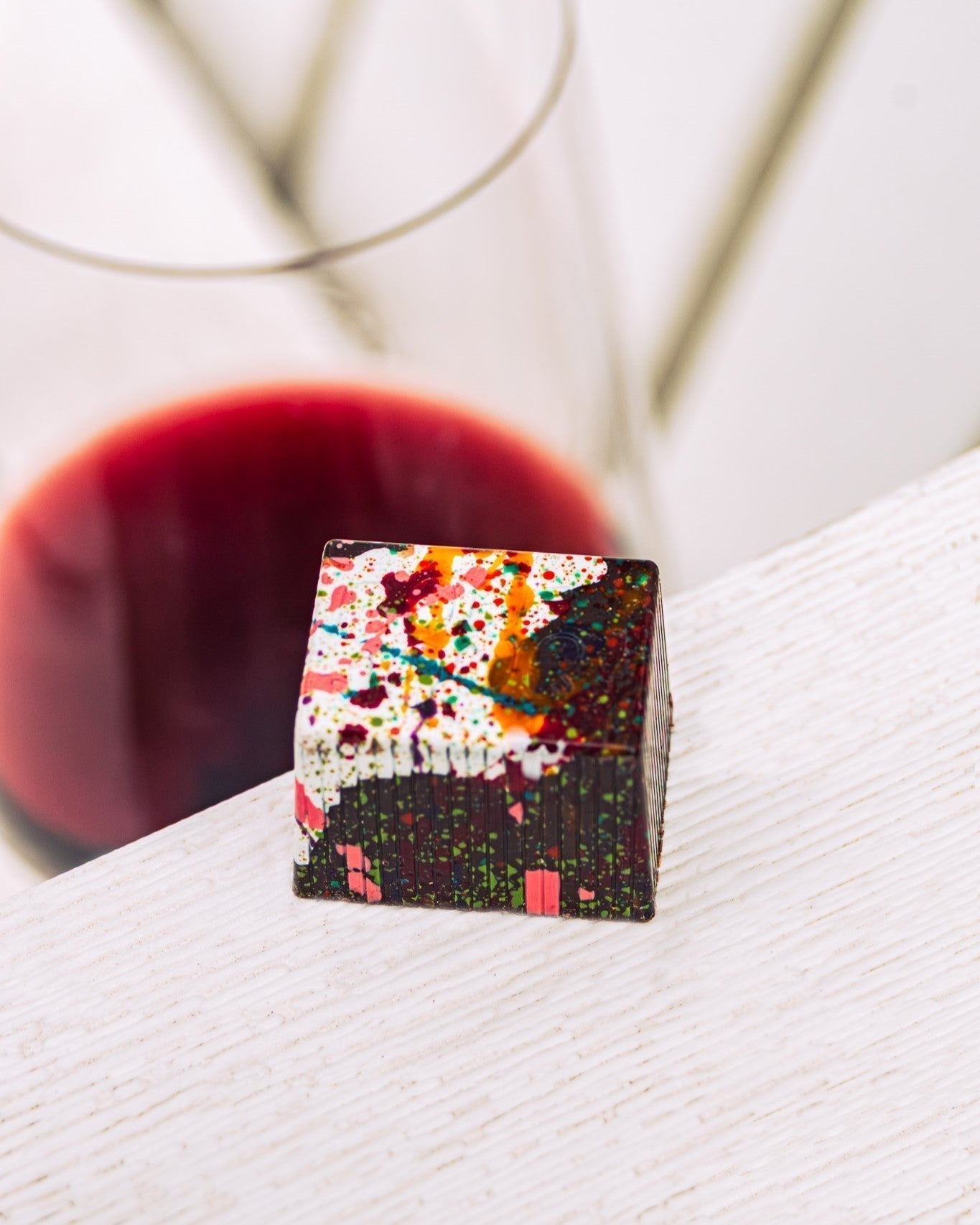 Bon with paint splatters on a table, wine glass with some red wine in background.