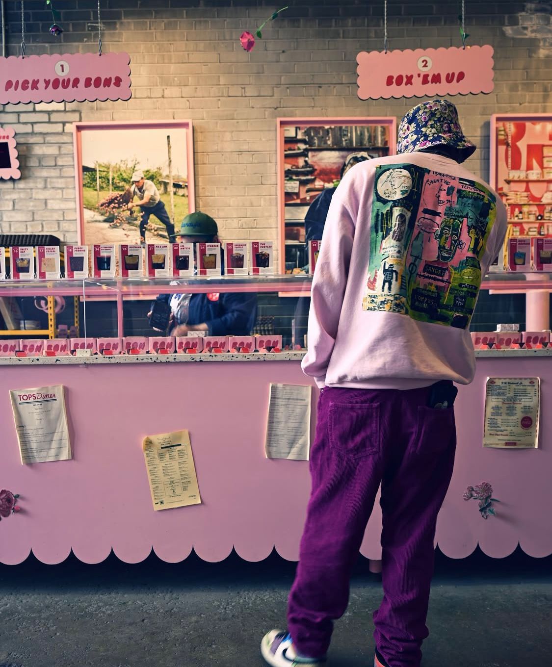 A man in a pink and purple outfit browsing the pink display cases at Bon Bon Bon Midtown