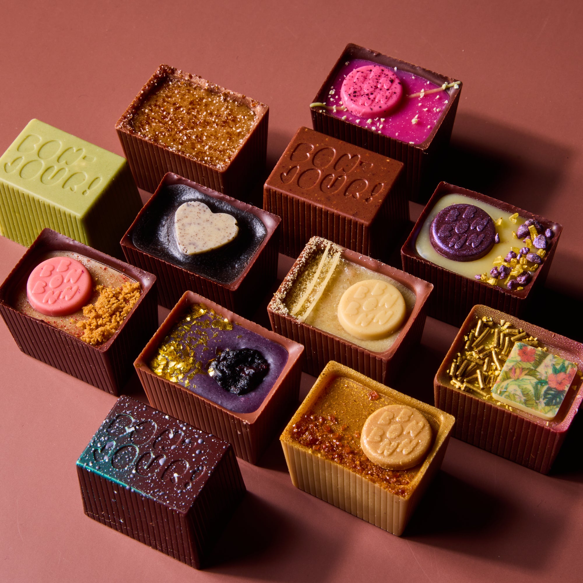 Assorted chocolate truffles with various toppings on a brown background
