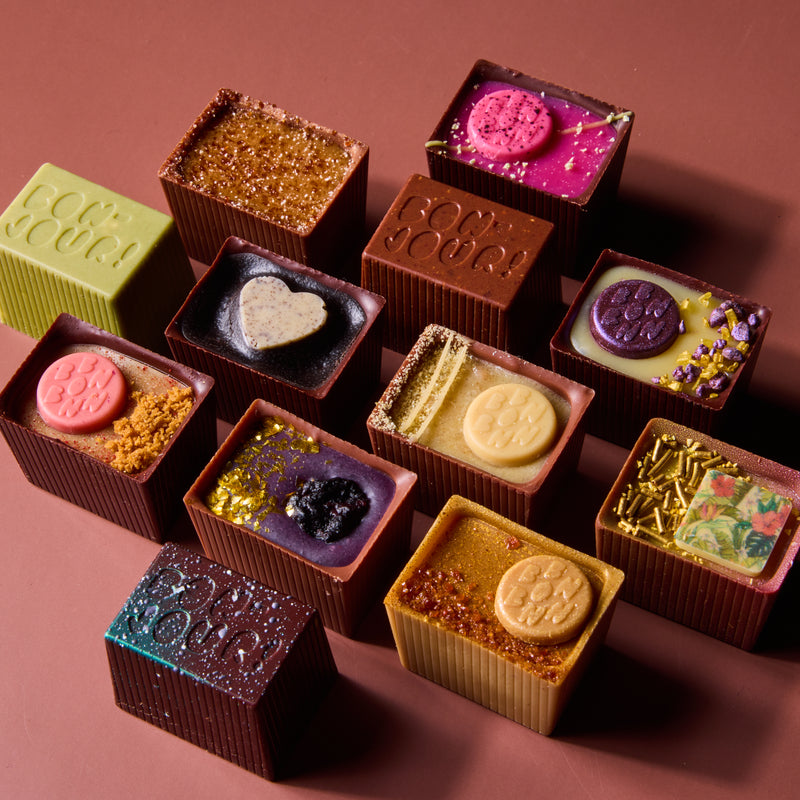 Assorted chocolate truffles with various toppings on a brown background