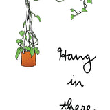 A greeting card with an illustration of a potted plant hanging from the top of the card, with the phrase 'Hang in there' written at the bottom.