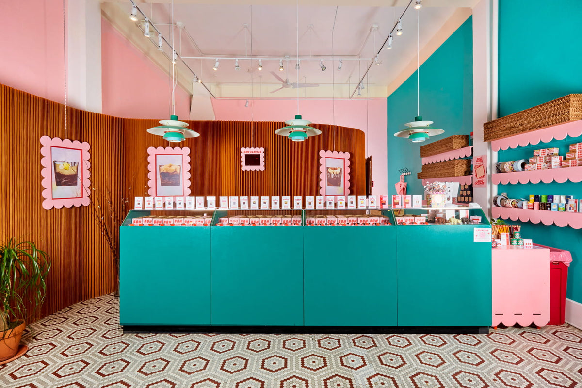 A wide shot of the interior of Bon Bon Bon's retail location in Ann Arbor, Michigan, with a teal counter showcasing all the Bons and framed artwork of the Bons on the wall