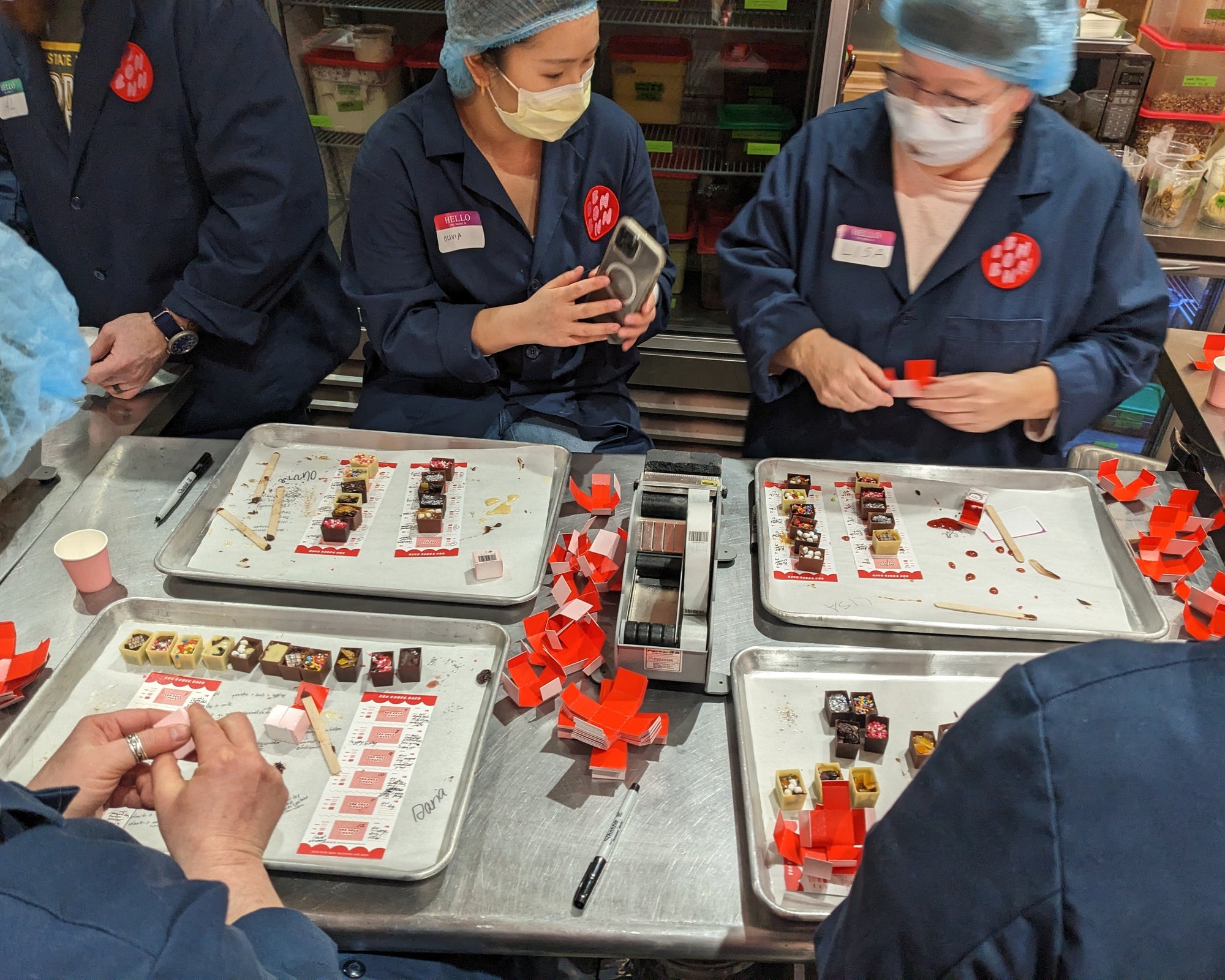 an action photo of four workshop participants packaging bonbons at their stations.